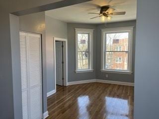 unfurnished bedroom with ceiling fan, a closet, and dark wood-type flooring