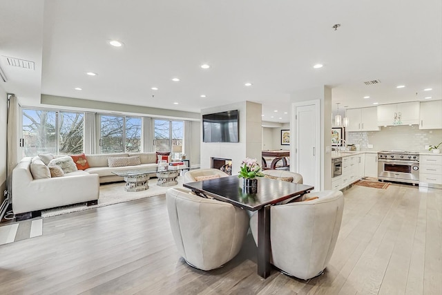 dining space with sink, a large fireplace, and light wood-type flooring