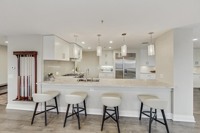 kitchen featuring white cabinetry, sink, kitchen peninsula, and stainless steel built in refrigerator