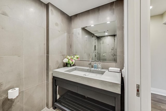 bathroom featuring tile walls, vanity, hardwood / wood-style flooring, and a shower