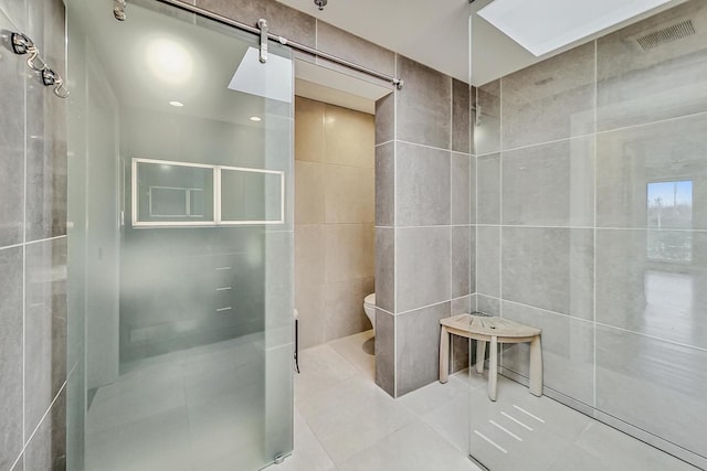 bathroom with tile walls, tile patterned floors, and toilet