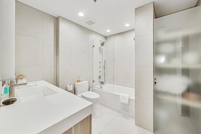 full bathroom featuring tile walls, vanity, tile patterned floors, toilet, and tiled shower / bath