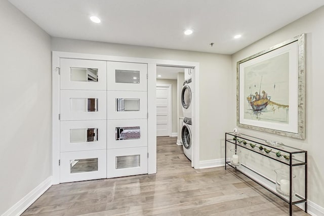 laundry area featuring stacked washer / dryer and light hardwood / wood-style flooring