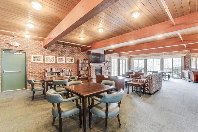 dining room featuring a brick fireplace, wooden ceiling, carpet flooring, beamed ceiling, and brick wall