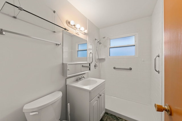 bathroom featuring vanity, toilet, and a tile shower