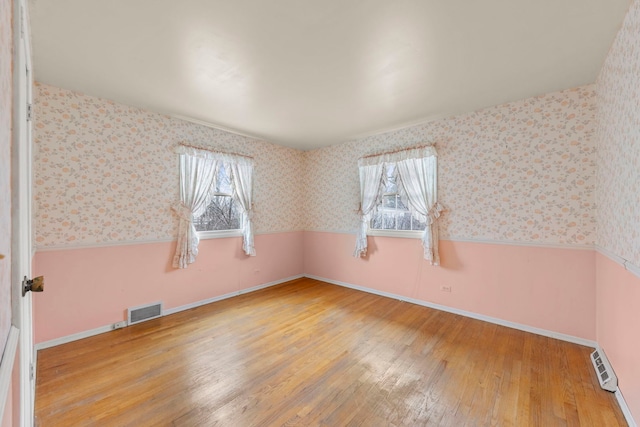 spare room featuring wood-type flooring and a healthy amount of sunlight