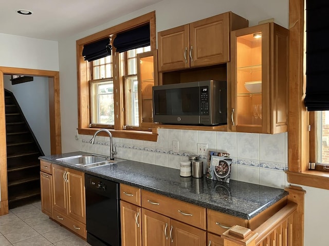 kitchen featuring dark stone countertops, light tile patterned floors, sink, black dishwasher, and decorative backsplash