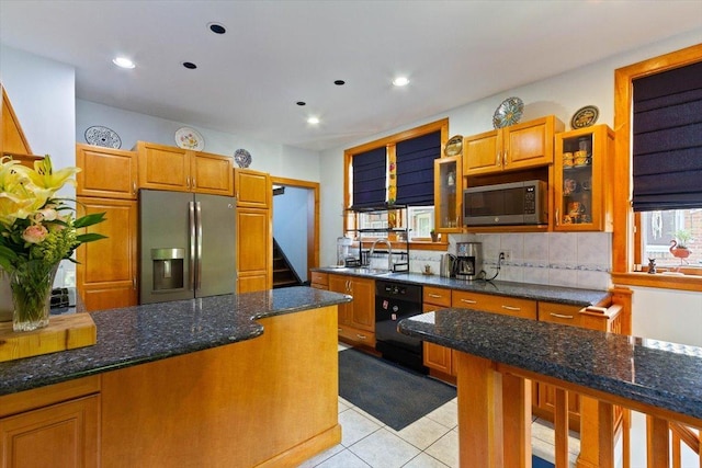 kitchen featuring dark stone countertops, sink, appliances with stainless steel finishes, light tile patterned flooring, and decorative backsplash