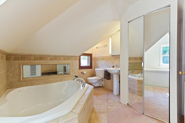 bathroom with lofted ceiling, toilet, and tiled tub