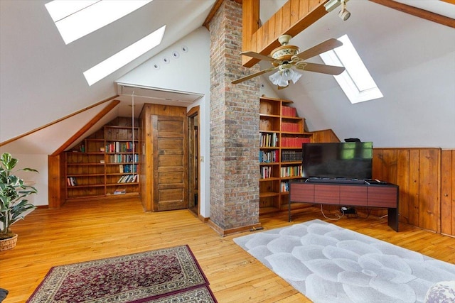 bonus room with wood-type flooring, vaulted ceiling with skylight, built in shelves, and wooden walls