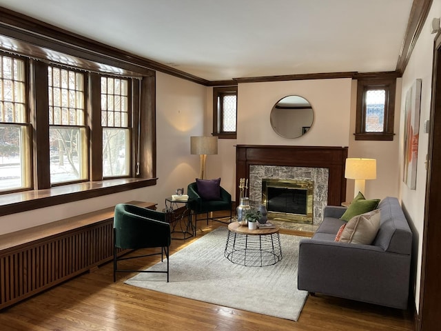 sitting room with a fireplace, radiator, crown molding, and wood-type flooring