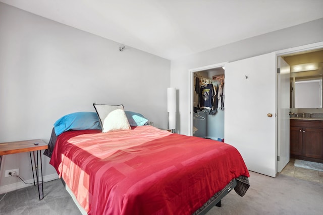 carpeted bedroom featuring a closet, a walk in closet, and ensuite bath