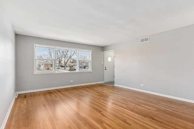 spare room featuring baseboards, visible vents, and light wood-style floors