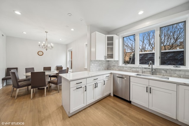 kitchen with sink, hanging light fixtures, stainless steel dishwasher, tasteful backsplash, and white cabinetry