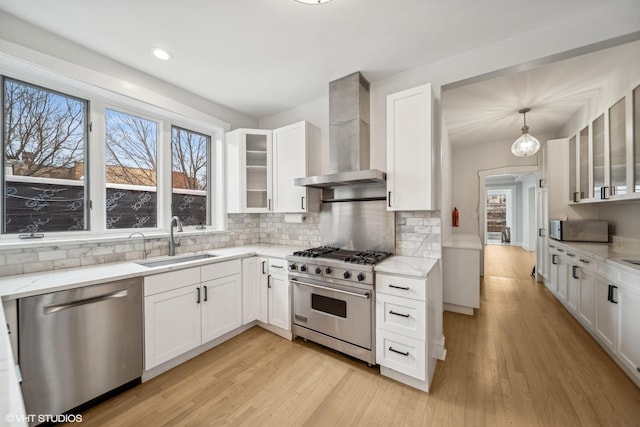 kitchen featuring white cabinets, sink, wall chimney exhaust hood, appliances with stainless steel finishes, and tasteful backsplash