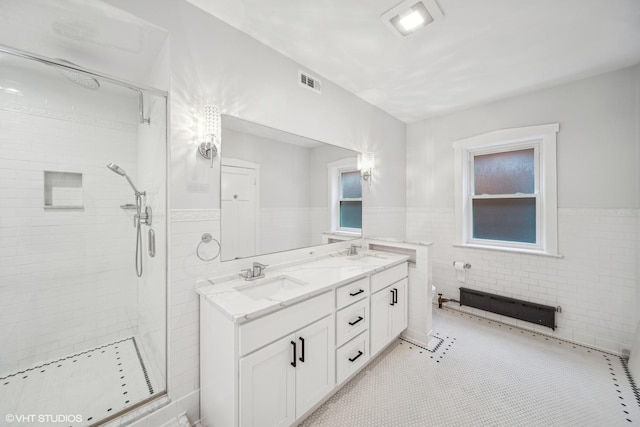 bathroom with tiled shower, vanity, tile patterned flooring, and tile walls