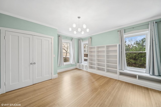 unfurnished bedroom with a closet, ornamental molding, light hardwood / wood-style flooring, and a chandelier