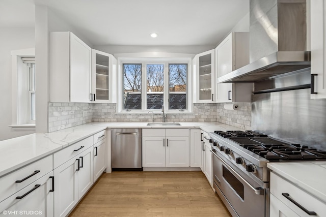 kitchen with white cabinets, stainless steel appliances, wall chimney exhaust hood, and sink