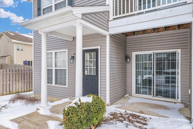 snow covered property entrance featuring a balcony