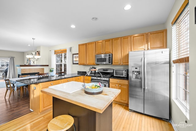 kitchen with pendant lighting, appliances with stainless steel finishes, a center island, a wealth of natural light, and a breakfast bar