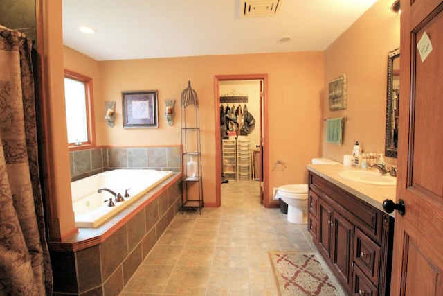 bathroom with vanity, toilet, and tiled tub