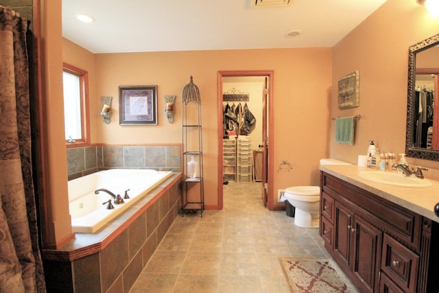 bathroom featuring vanity, toilet, and tiled tub