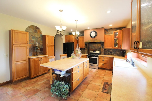 kitchen featuring a center island, black refrigerator, sink, gas stove, and a kitchen bar