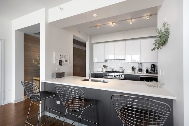 kitchen featuring a kitchen breakfast bar, sink, tasteful backsplash, white cabinetry, and kitchen peninsula