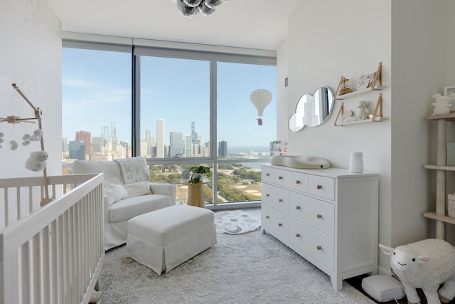 bedroom featuring light carpet, a nursery area, and expansive windows