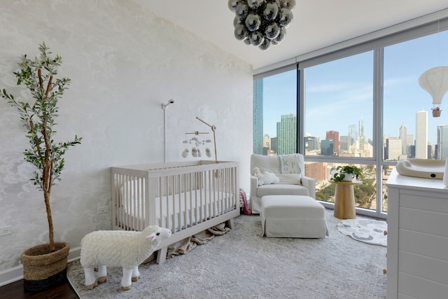 bedroom featuring a crib, hardwood / wood-style flooring, and floor to ceiling windows