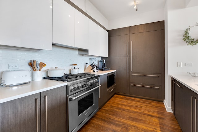 kitchen featuring dark brown cabinetry, high end stove, tasteful backsplash, dark hardwood / wood-style flooring, and white cabinetry