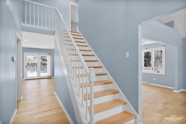 staircase with hardwood / wood-style floors and french doors