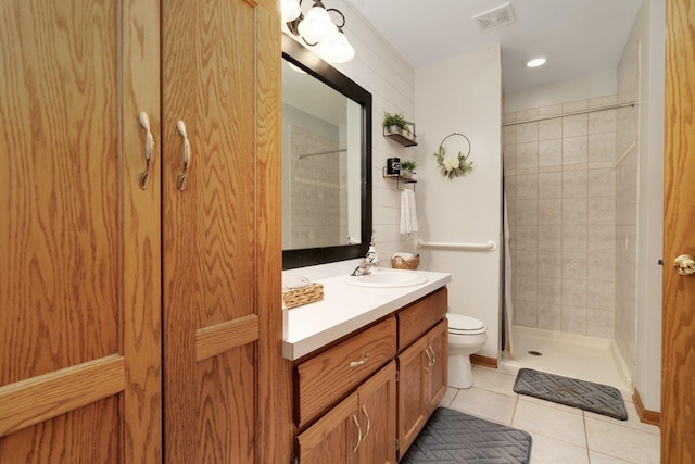 bathroom with a tile shower, tile patterned flooring, vanity, and toilet