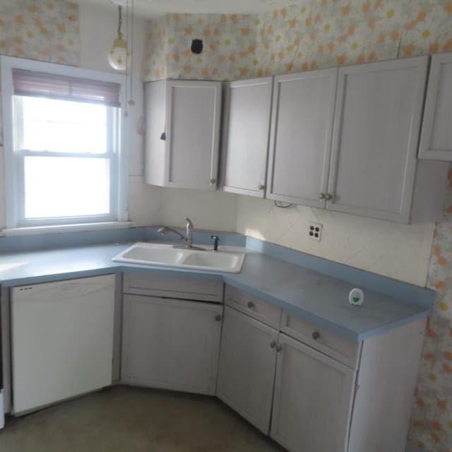 kitchen with dishwasher, white cabinets, hanging light fixtures, and sink