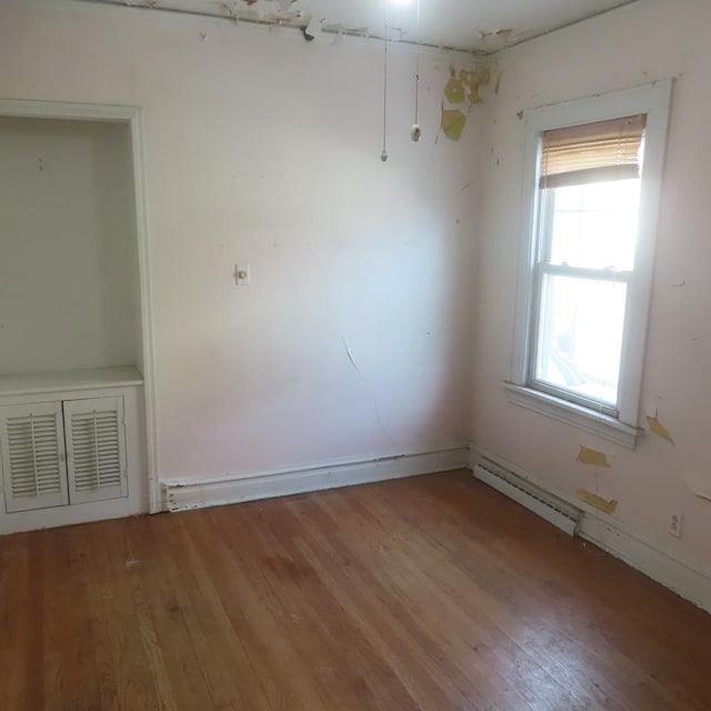 unfurnished room with a baseboard radiator and hardwood / wood-style flooring