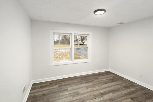 empty room featuring dark wood-type flooring and a textured ceiling