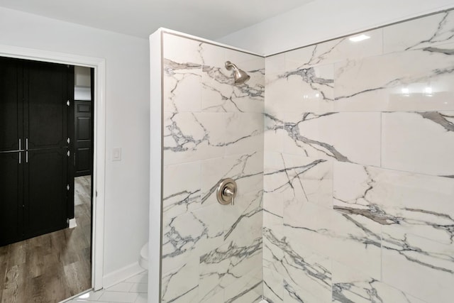 bathroom with a tile shower and toilet