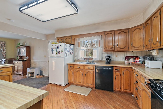 kitchen featuring light wood-type flooring, backsplash, sink, and black appliances