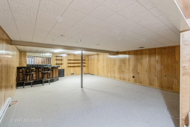 basement featuring a baseboard radiator, indoor bar, and wooden walls