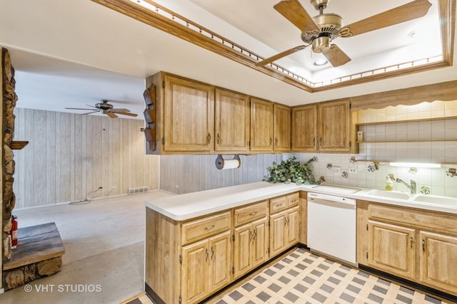 kitchen with dishwasher, sink, ceiling fan, and wood walls