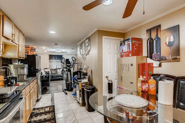 kitchen with dark stone counters, ceiling fan, crown molding, stainless steel stove, and light tile patterned flooring