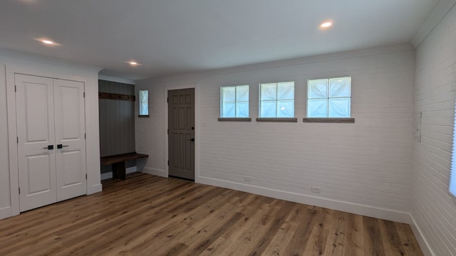 unfurnished room with hardwood / wood-style floors, brick wall, and ornamental molding