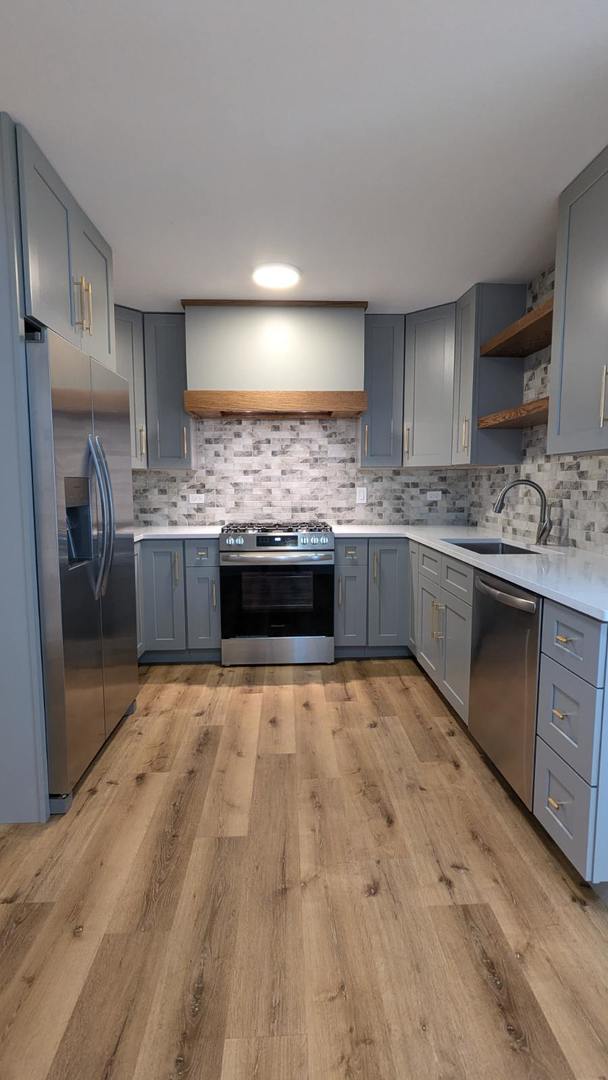 kitchen with sink, stainless steel appliances, light hardwood / wood-style floors, and custom exhaust hood