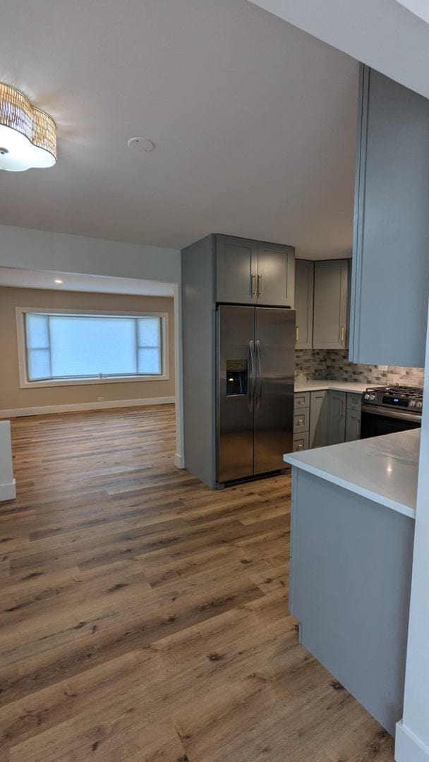 kitchen featuring appliances with stainless steel finishes, backsplash, gray cabinets, and dark wood-type flooring