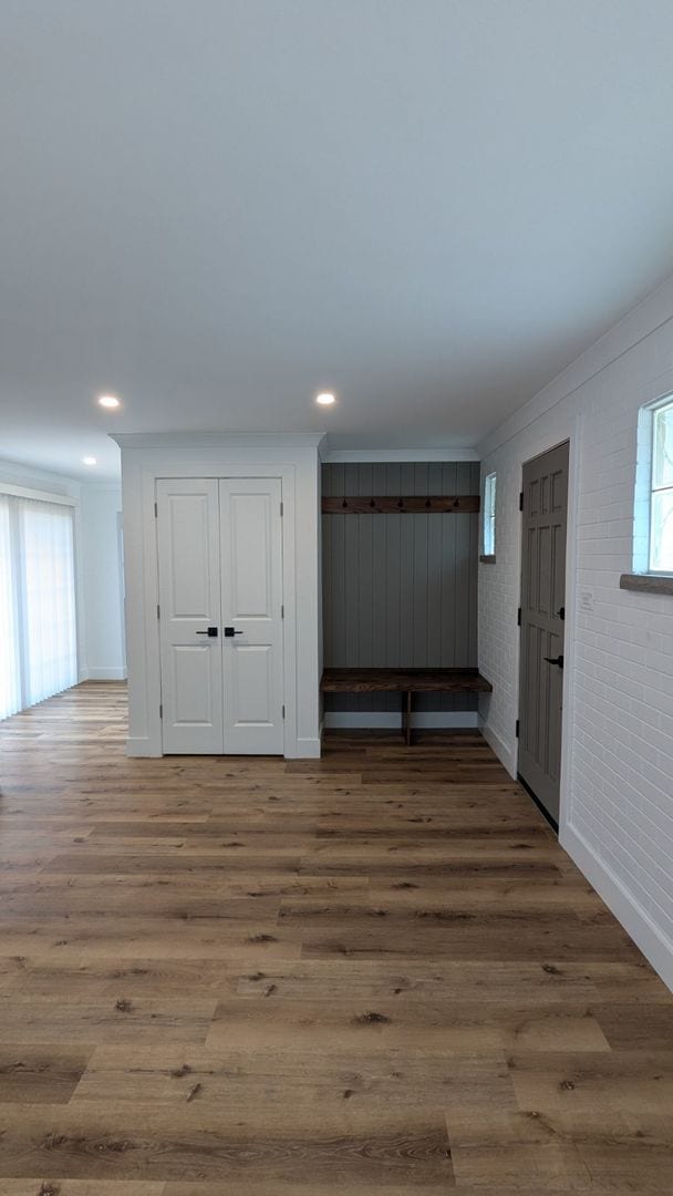 interior space featuring wood-type flooring, crown molding, and brick wall