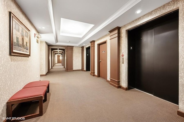 corridor featuring a raised ceiling, elevator, light carpet, and decorative columns