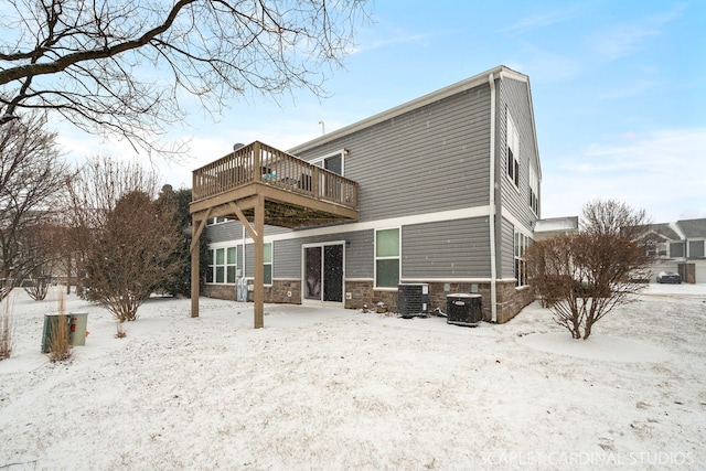 snow covered back of property featuring cooling unit and a deck