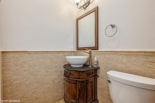 bathroom with vanity, toilet, and tile walls