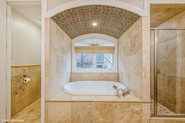 bathroom with vaulted ceiling, tile walls, and independent shower and bath