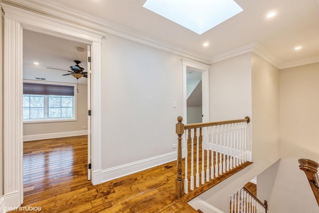 hallway with a skylight, crown molding, and hardwood / wood-style floors